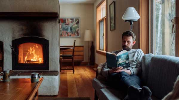 A man reading by a fire.