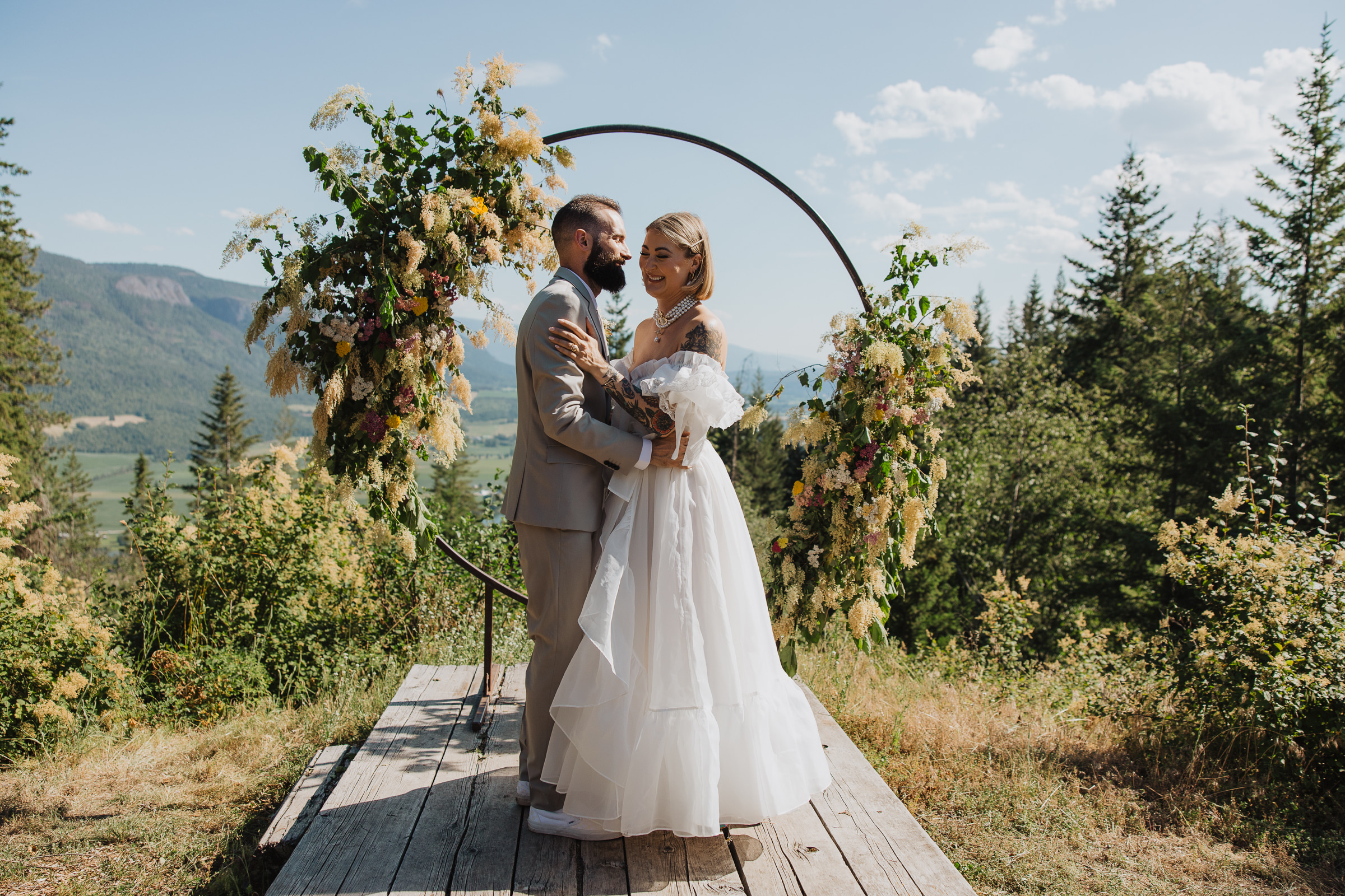Cydney & Michael Bride and groom standing beneath a circular wedding arch during a woodland micro wedding at Tin Poppy Retreat.